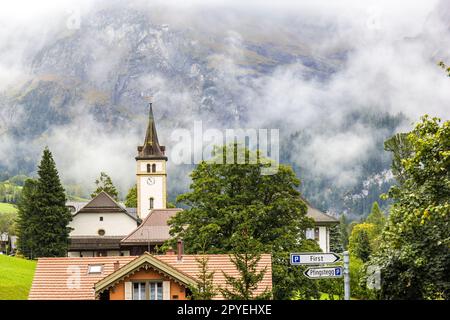 La chiesa riformata nel famoso villaggio ricreativo svizzero Grindelwald con la montagna nebbiosa sullo sfondo Foto Stock