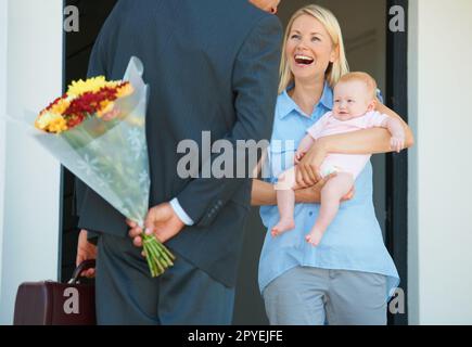 HES un romantico senza speranza. un uomo che sorprende sua moglie con i fiori. Foto Stock