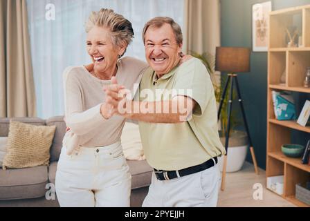 Felice, ballare e coppia anziana in salotto, sorridere e divertirsi mentre si è sciocchi a casa loro insieme. Famiglia felice, amore e uomo con donna che balla, ride e goffa mentre si gode la pensione Foto Stock