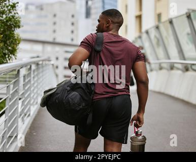 Uomo nero, schiena o borsa per il fitness sul ponte cittadino, strada o strada con attrezzatura da allenamento, bottiglia d'acqua per allenamento o kit per esercizi. Runner, atleta sportivo o personal trainer in città per raggiungere la palestra per il benessere Foto Stock