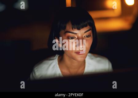 Niente rompe la sua attenzione. una giovane donna d'affari che usa un computer durante una tarda notte al lavoro. Foto Stock