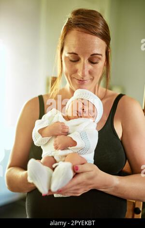 HES seduto sulle mie mani come se fosse una sedia. un ragazzino stanco che dorme con gli occhi chiusi mentre sua madre lo tiene in mano a casa. Foto Stock