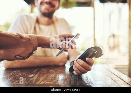 Al giorno d'oggi non sono più necessari portafogli. un cliente che effettua un pagamento wireless in una caffetteria. Foto Stock