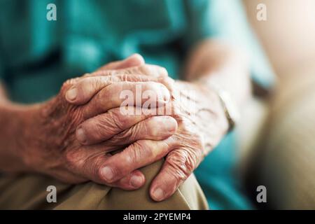 Le mani raccontano davvero una storia. un uomo anziano irriconoscibile seduto con le mani sul ginocchio all'interno. Foto Stock