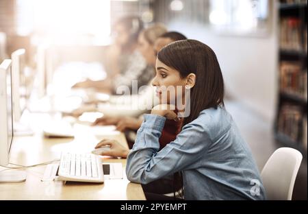 Questo sembra interessante. studenti universitari che lavorano su computer nella biblioteca del campus. Foto Stock