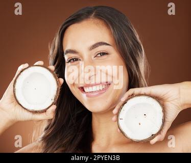 Viso, bellezza della pelle e donna con noce di cocco in studio sullo sfondo. Benessere, cosmetici biologici e ritratto di modello femminile con frutta, prodotto o cibo per una dieta sana, nutrienti o olio di cocco Foto Stock