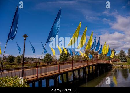 Un ponte pedonale decorato con bandiere sul fiume Deschutes nel quartiere Old Mill di Bend, Oregon, Stati Uniti. Foto Stock