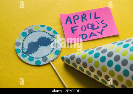 Berretto, topper con baffi e note con la frase "April Fool's Day" su sfondo giallo Foto Stock