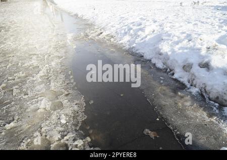 Flusso di primavera, il ghiaccio e la neve e abbagliante luce del sole, il riflesso del cielo in acqua Foto Stock