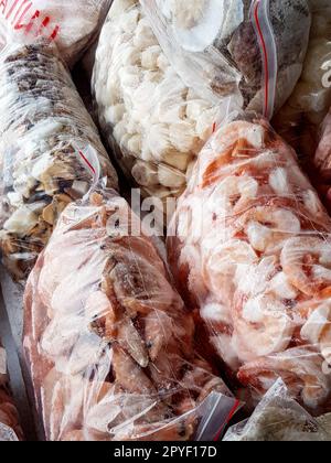 Ci sono molti grandi sacchetti di plastica con i gamberetti surgelati crudi e bolliti sul banco del mercato del pesce. Foto Stock