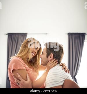 Il tuo sorriso fa saltare il mio cuore un battito. una giovane coppia felice che condivide un momento affettuoso a letto. Foto Stock