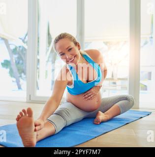 Mantenersi in forma e sicuramente si sente bene. una donna incinta che si sta allenando su un materassino da ginnastica a casa. Foto Stock