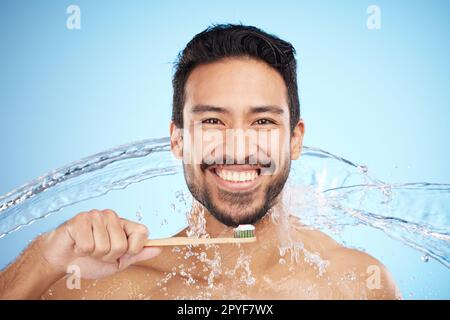 Spruzzi d'acqua, ritratti o uomo che spazzolano i denti in studio con spazzolino per denti bianchi o igiene orale. Viso, dentifricio o persona felice pulire o lavare la bocca con un sorriso dentale sano Foto Stock