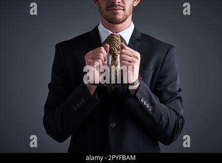 Criminale aziendale. Studio shot di un uomo d'affari manettato con un cappio legato intorno al collo per una cravatta su uno sfondo grigio. Foto Stock