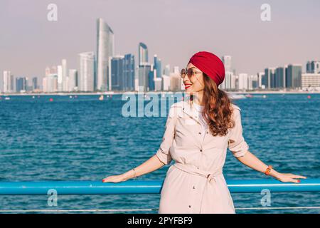 Ragazza indiana Hapyy sul lungomare della città di Abu Dhabi negli Emirati Arabi Uniti, con vista panoramica dello skyline della città e grattacieli Foto Stock