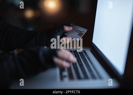 Gli hackers arent hanno paura di aiutarsi ai vostri possessi. un hacker irriconoscibile che utilizza un notebook per effettuare un hack in un account di credito. Foto Stock