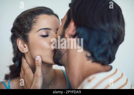 Theres nessuna cosa come troppi baci. una giovane coppia affettuosa che condivide un bacio sul divano di casa. Foto Stock