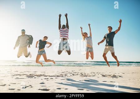 Woop Woop estate pausa è qui. un gruppo di giovani amici che saltano entusiasticamente in aria in spiaggia. Foto Stock