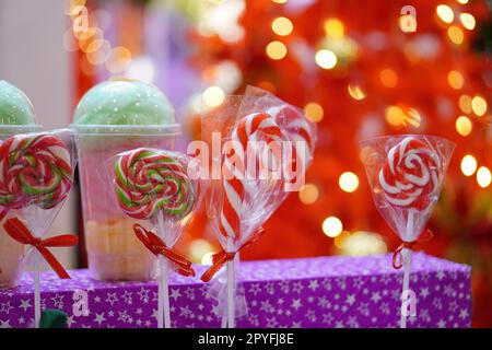 Caramelle natalizie rosse e bianche e lecca-lecca con sfondo rosso sfocato Foto Stock