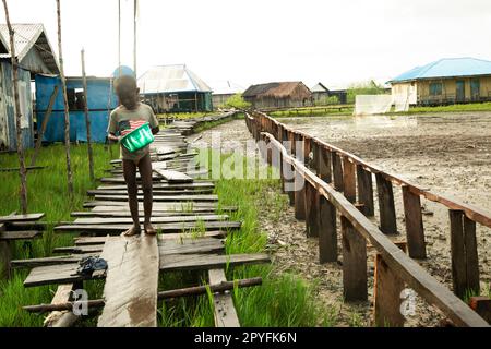 Ondo state, Nigeria - 2nd maggio 2023 - Un ragazzo che cammina attraverso una baraccopoli inquinata nella comunità fluviale di Abereke nello Stato Ondo. Foto Stock