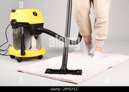 Donna tappeto hoovering su sfondo grigio, primo piano Foto Stock