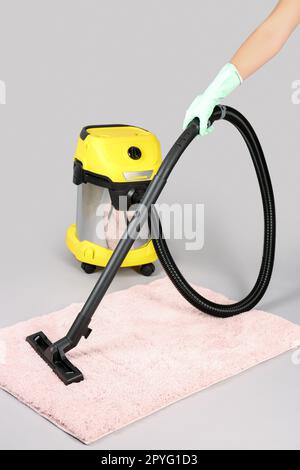 Donna tappeto hoovering su sfondo grigio Foto Stock