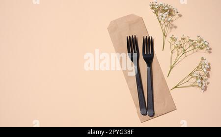 Forchette nere in plastica su sfondo beige, articoli da picnic monouso, vista dall'alto Foto Stock