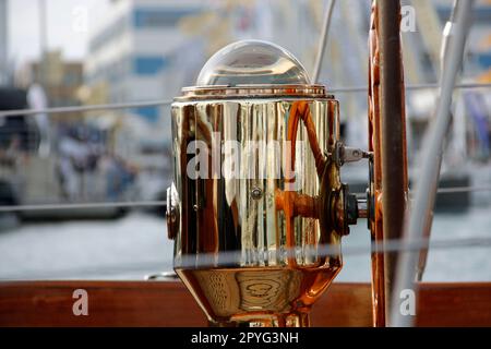 Una bussola in vecchio stile dorata su una barca sullo sfondo di barche su un porto Foto Stock