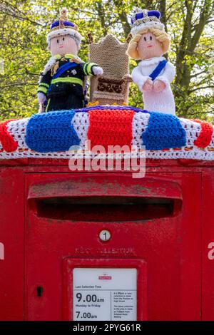 Un omaggio a maglia a re Carlo e regina Camilla su una casella postale inglese suburbana per la loro incoronazione il 6th maggio 2023. Foto Stock