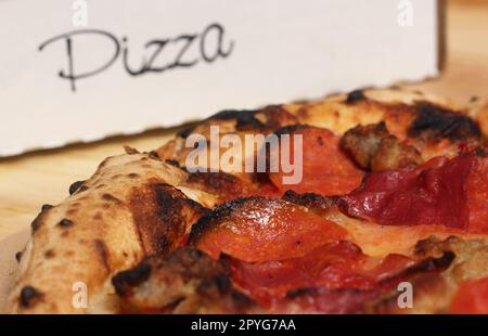 Pizza fresca su tavolo in legno al ristorante affettato e pronto a mangiare Foto Stock