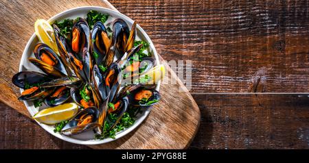 Un piatto di cozze al vapore servito con prezzemolo e limone Foto Stock