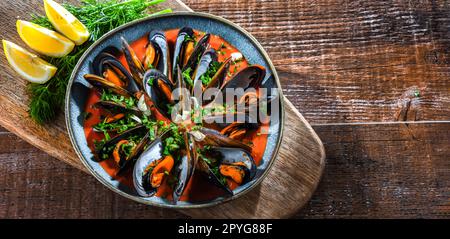 Un piatto di cozze in salsa di pomodoro servito con prezzemolo e limone Foto Stock