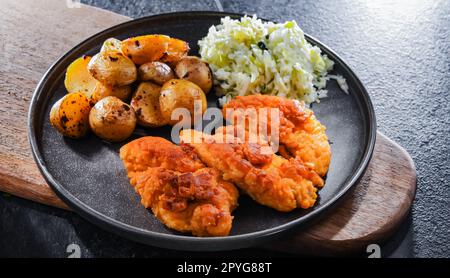 Cotolette di pollo impanate servite con patate e cavolo Foto Stock