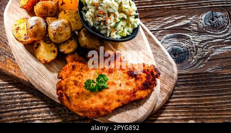 Cotoletta di pollo ricoperta di pangrattato con patate e cavolo Foto Stock