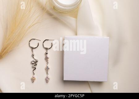 Elegante set di gioielli di orecchini in argento con gemma e scatola regalo mock su spazio copia. Gioielli stile minimalista. Concetto di bijouterie fatto a mano. Foto Stock