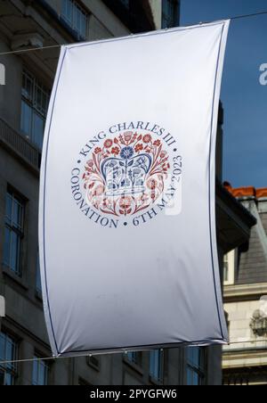 Bandiera con l'emblema del logo dell'incoronazione di Re Carlo il terzo appeso nello Strand, Londra. Foto Stock