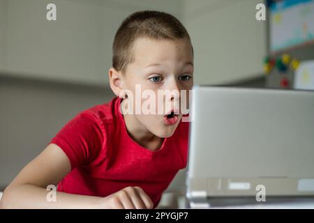 Boy 6-10 completa le lezioni scolastiche e i compiti online in cucina, guardando il tablet. Istruzione a distanza. Foto Stock