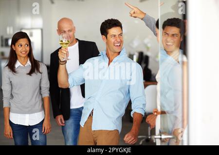 Sviluppare una cattiva reputazione sul posto di lavoro. Un uomo ubriaco con un bicchiere di vino in mano in un ufficio sociale. Foto Stock