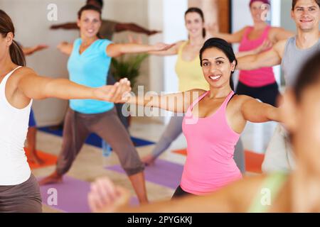 Lezione di yoga. Ritratto di una giovane donna attraente godendo di una classe di yoga circondata da altri studenti. Foto Stock