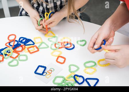 Irriconoscibile donna corta, mani femminili che collegano un colorato elemento a catena, costruttore di puzzle. Autismo e disturbo dell'adhd Foto Stock