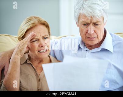 Oneri di bilancio. una coppia anziana che osserva frustrato mentre passa il loro lavoro di ufficio insieme. Foto Stock