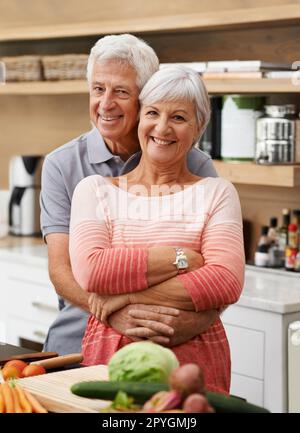 Allenarlo ad essere il mio masterchef. Marito maturo abbracciando con amore sua moglie da dietro. Foto Stock