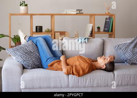 Donna più pulita stanca, sonno e divano per rilassarsi per stanchezza, benessere e salute mentale dopo la pulizia casa. Esperto di igiene, burnout e dormire sul divano del soggiorno per riposo, salute o stress a casa Foto Stock