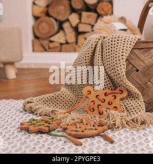 Giocattolo in legno per bambini con fori per allacciare il filo arancione sulla coperta beige sullo sfondo del caminetto. Telaio quadrato Foto Stock