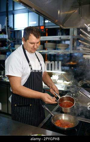 Lo chef prepara la salsa di pomodoro per la pasta nella padella Foto Stock