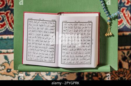 Corano, perline di preghiera e moschea con un libro aperto e un rosario in una stanza Santa vuota o in un tempio pronto per pregare. Misbaha islamica, tasbih o sibha e scritture in un luogo di culto musulmano per l'eid Foto Stock