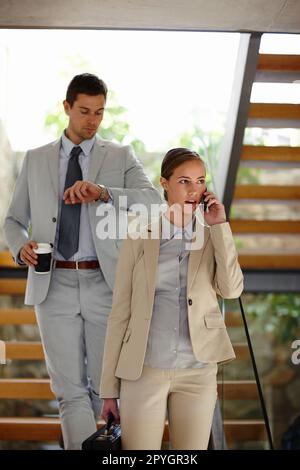 Il tempo si ferma per nessuno. Un breve scatto di un giovane uomo d'affari e di una donna d'affari impegnati che camminano giù una rampa di scale. Foto Stock