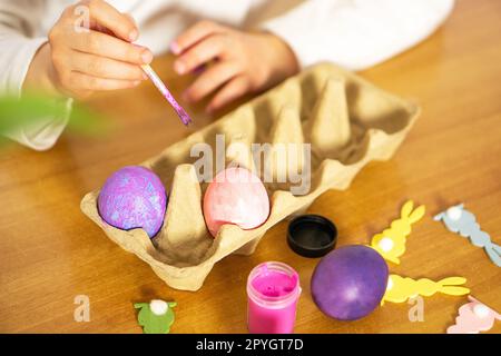 Primo piano delle mani dei bambini che dipingono le uova di Pasqua su un tavolo di legno. Buona Pasqua. Preparazione alla Pasqua. Foto Stock