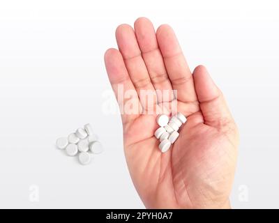Una manciata di pillole bianche in mano su uno sfondo bianco Foto Stock