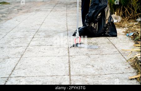 Volontario che raccoglie la maschera medica usata vicino alla bottiglia di plastica nella sacca di plastica della spazzatura per la pulizia della strada urbana. Ripulire la spazzatura della comunità. Giornata mondiale dell'ambiente, salvare la terra. Rifiuti medici. Foto Stock